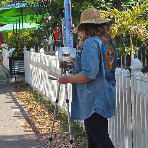 A photograph of a woman doing a plein air painting.