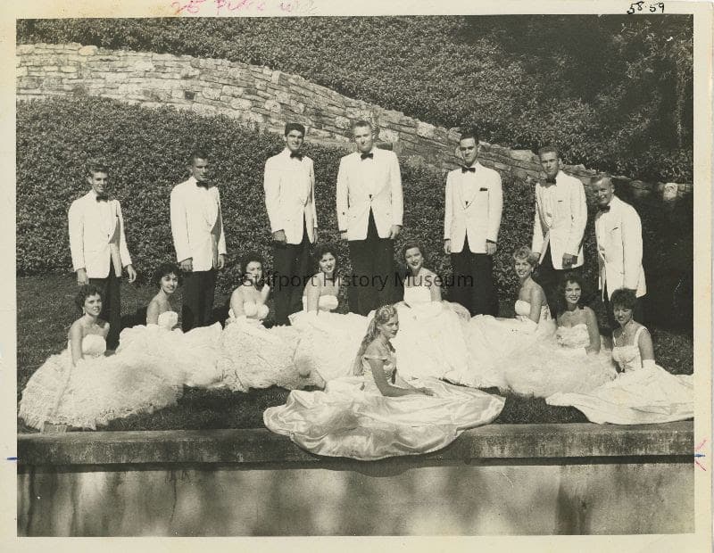 A black and white photograph of the members of the Baker's Dozen in posing for group photos in formal wear outside.